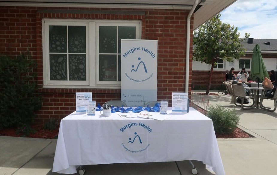 Margins Health outreach table with a banner and information for Medi-Cal members at a community event
